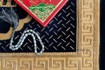 Muslim Holy Quran and rosary or tasbih with praying mat rug or sejadah