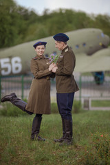 Young adult man and woman in the uniform of pilots of the Soviet Army of the period of World War II. Military uniform with shoulder straps of a major and a cap on his head. Photo in retro style. © Kozlik_mozlik