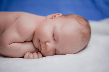 Sweet sleeping newborn baby boy on white bedspread