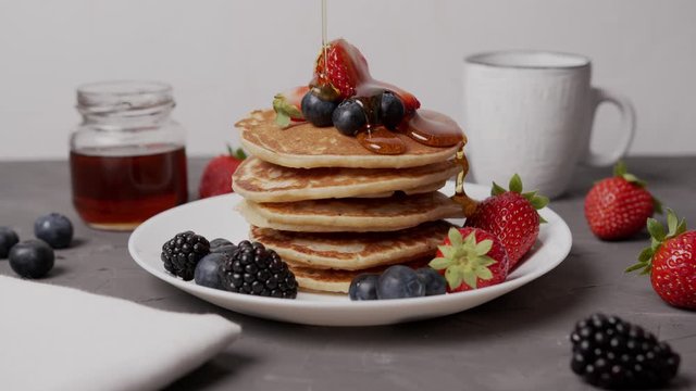 Maple syrup is poured over a stack of pancakes with strawberries, blueberries, blueberries in slow motion. Chef's Table, cooking show and Food Network inspired footage