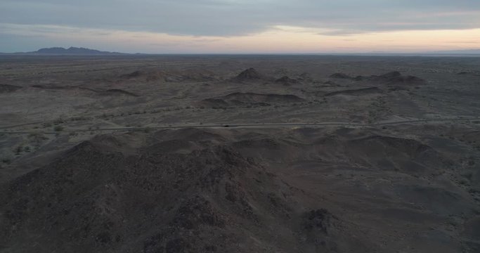 Flying over mountains to see vehicle on side of the road. Martian ladscape at dusk