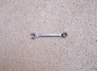 A small steel wrench with cement ground