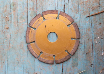 An orange saw blade placed on a blue wood floor
