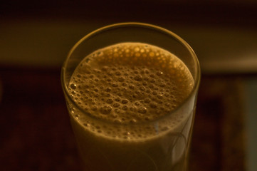 A glass with whipped milk in blender making bubbles