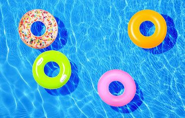 Different inflatable rings floating in swimming pool, top view