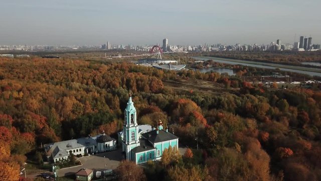 4K quality aerial sunny autumn day video scenic view of park, distant city, old blue walled vintage church and hills in Krylatskoye suburb area near Moscow River in Moscow, Russia