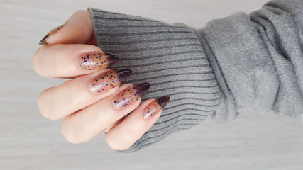 Female hand with long nails and black manicure with bottles of nail polish