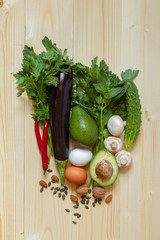 Fresh vegetables, nuts and foods for a balanced diet on a light wooden background, top view