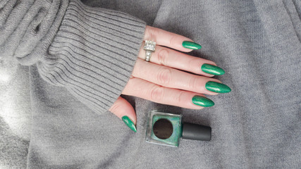 Female hand with long nails and green manicure with bottles of nail polish © Tatiana