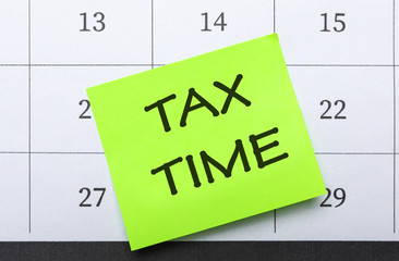 Reminder note with words TAX TIME on calendar, top view