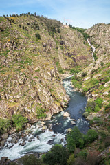 Landscape of the Paiva gorge with the Paiva river and its rapids in the foreground and the Aguieiras waterfall in the background, near Arouca in Portugal.