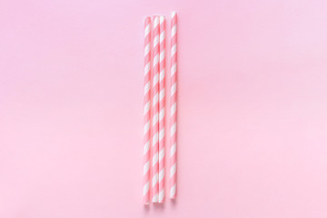 Pastel paper straws with white stripes on soft pink background. Zero waste party concept. Flat lay style with copy space.