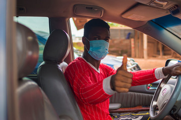 young handsome african taxi driver wearing face mask preventing, prevent, prevented himself from the outbreak in the society and did thumbs up