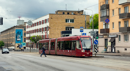 Obraz premium City street in spring, a man crossing the street moves to the tram