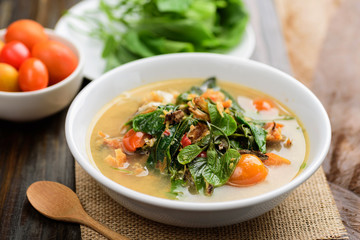 Northern Thai food (Kang Pak Seaw), Spicy soup with Bauhinia Purpurea leaf and roasted smoked fish in a bowl on wooden background