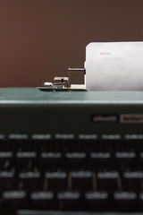 Antique Typewriter. Vintage Typewriter Machine Closeup Photo. "Hola" text typed, white sheet. © viajeroscreativos
