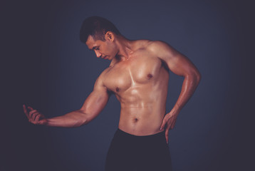 Fototapeta premium Muscular model Asian young man on Gray background. Portrait of strong brutal guy with trendy hairstyle. Sexy naked torso, six pack abs. Male flexing his muscles. Sport workout bodybuilding concept.