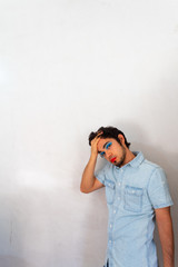 Non-binary bearded young Hispanic man on a white background, with flamboyant makeup posing, red lips and blue eye shadows