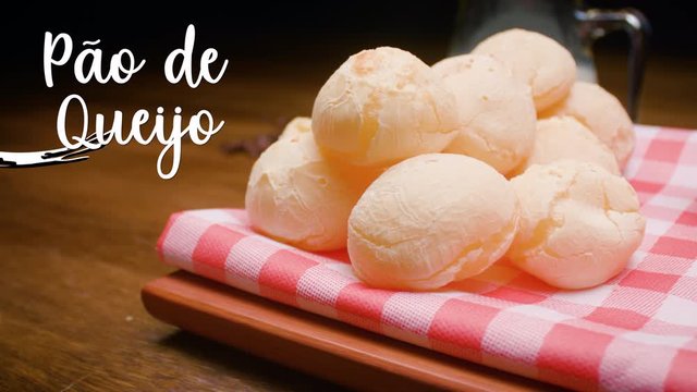 A typical Brazilian food, P&atilde;o de queijo. Next to it appears written in Portuguese P&atilde;o de queijo