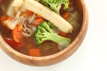 Homemade sausage and broccoli vegetable soup in wooden bowl