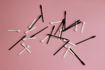 mascara brushes and shadow applicators are scattered carelessly on a pink background