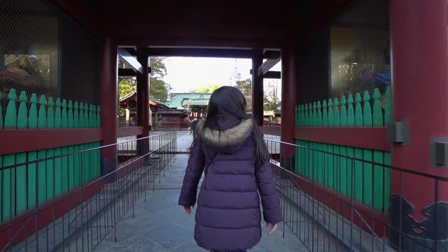 A girl walks past the entrance to a Shinto temple in Tokyo, Japan. Most of the temples in Japan have wooden constructions of great architectural value.