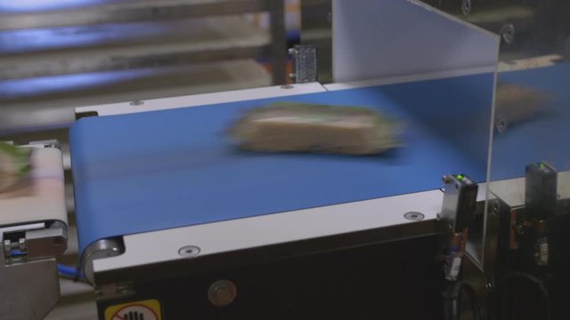Confectionery bars move fast along a belt in a factory production line.