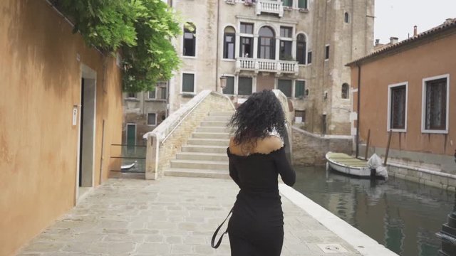 Curly girl walking and spinning on a bridge in Venice slow motion