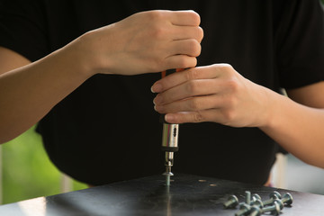Woman assembling furniture at home using  screwdriver. Close up.