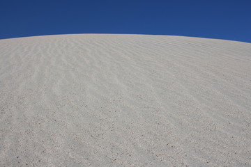 sand hill dunes in the desert against a blue sky of sand
