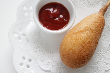Corn dog and ketchup on dish for fast food