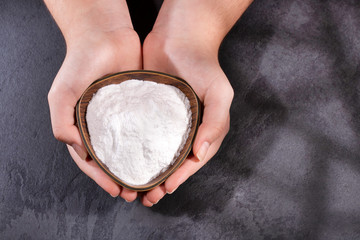 Female hands holding bowl of baking soda - wooden background