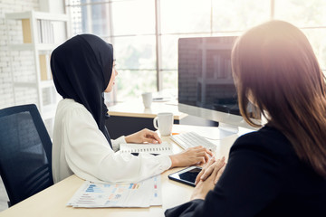 multiethnic asian female muslim workers working in office as team using computer to strategize and planning work, concept of diversity of culture different race type of people co-working together