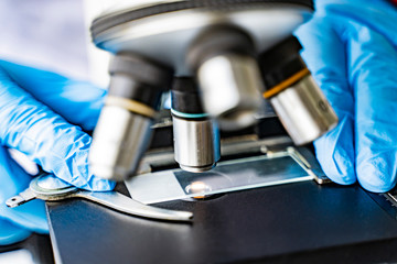 doctor wearing protective gloves using microscope researching corona virus microscopic cells testing vaccination cure, medical center lab china Wuhan world health organization research facilities