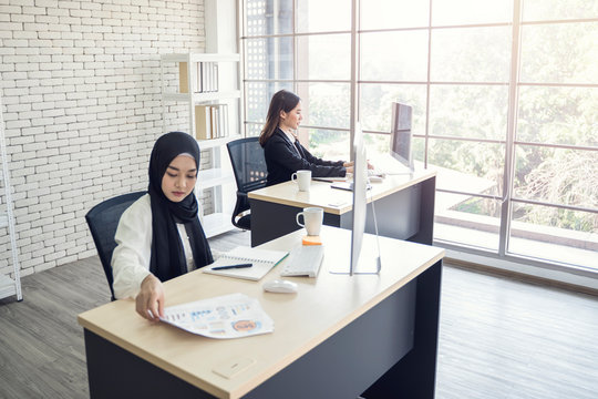 multiethnic asian female muslim workers working in office as team using computer to strategize and planning work, concept of diversity of culture different race type of people co-working together
