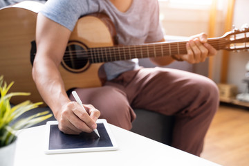Fototapeta premium Work from home playing guitar writing composing songs free time spending activity using laptop wearing face mask self isolation quarantine lockdown staying safe in protection from coronavirus covid-19