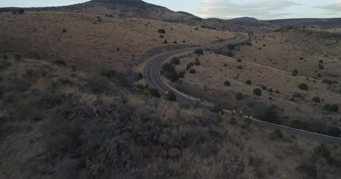Reveal over mountain shows van on road trip travelling around winding road