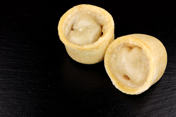 Two individual steamed steak and kidney puddings in suet pastry cases on a slate background