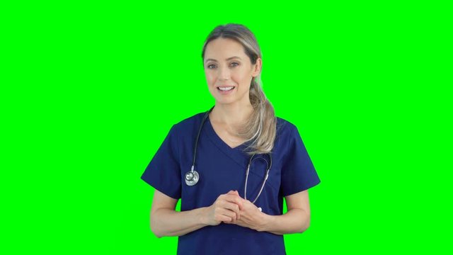 4K portrait of female nurse doctor on green screen isolated with chroma key. Woman standing looking at camera smiling and talking. Telemedicine concept. Remote medical assistance via video call