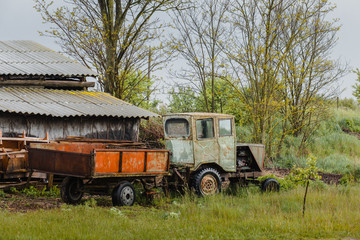 Old rural tractor with a hand-assembled trailer, without brand and name.