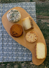 Top view of assorted cheeses on a rustic wooden board. Blue cheese, cured cheese, Manchego cheese, smoked cheese.