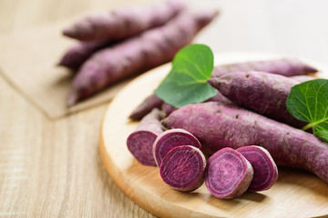 Raw purple sweet potatoes on wooden plate, organic vegetable 
