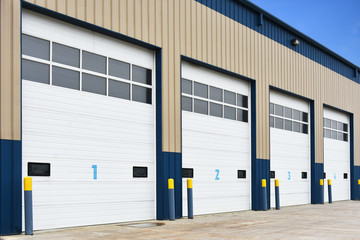 An image of a commercial building with large white numbered bay doors. 