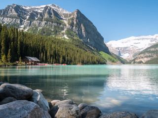 Turquoise glacier lake with boathouse surrounded by mountains, shot in Lake Louise area, Banff National Park, Alberta, Canada