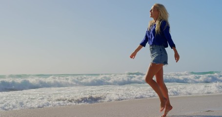 Woman walking on beach in the sunshine