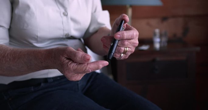 Woman checking blood sugar level on bed in bedroom at home
