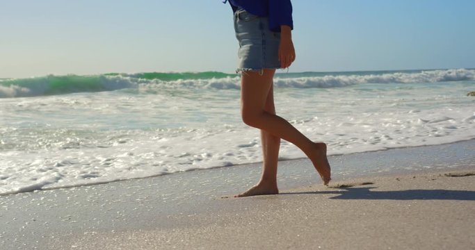 Woman walking on beach in the sunshine