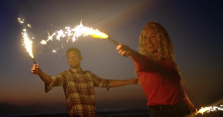 Couple dancing with sparklers on beach at dusk - Powered by Adobe