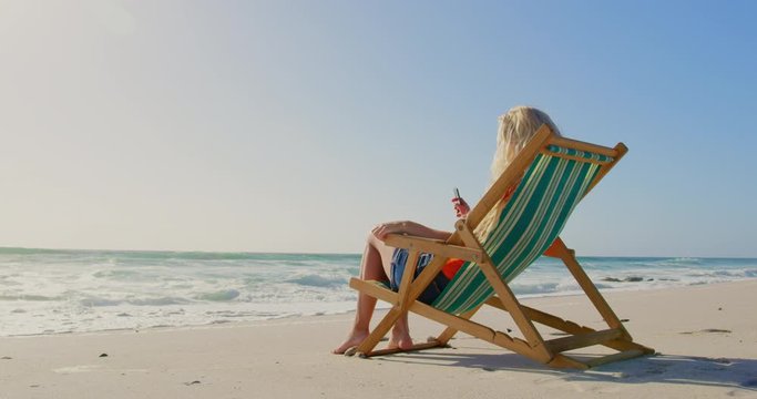 Woman relaxing on sun lounger at beach in the sunshine