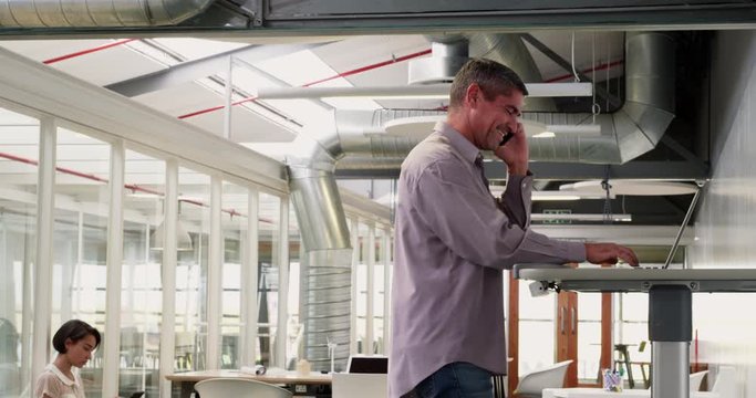 Businessman exercising on treadmill while talking on mobile phone in m